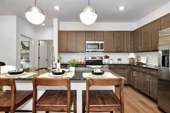 a kitchen with wooden cabinets and a island with wooden chairs